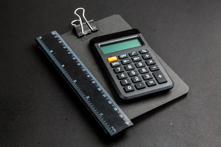 calculadora de vista inferior e régua no bloco de notas na mesa escura