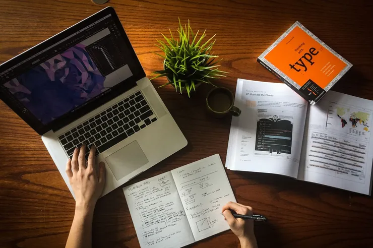 mesa com notebook e caderno e livro